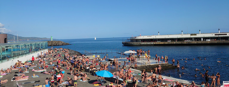 Badende am Meer mit Boot im Hintergrund