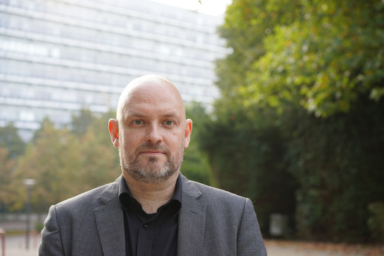 Porträt von Christian Deindl mit Mathe-Gebäude im Hintergrund, Querformat