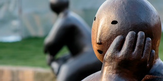 Massive stone statue in a thoughtful pose.